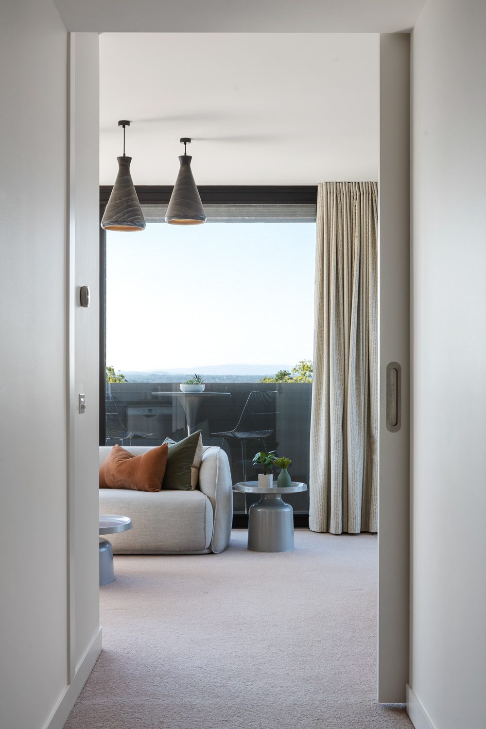 Sitting room opening to a balcony with hills beyond, inner-east new build